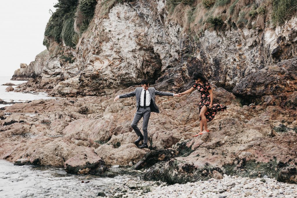 Jodi + Jade Howth engagement shoot climbing across the rocks in a suit