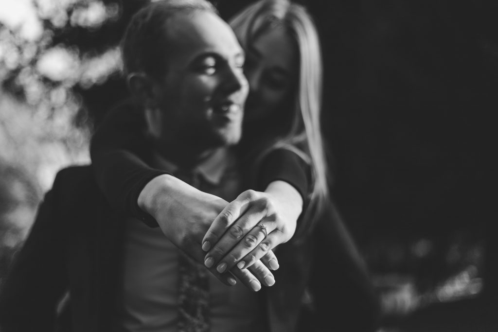 Luke and Kate having fun showing off her engagement ring in black and white