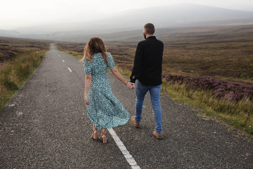 Anna and Colm couples photography in wicklow mountains walking down a road holding hands
